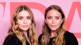 Mary-Kate and Ashley Olsen stand next to one another on the red carpet in black looks.