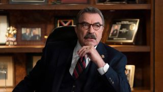 Tom Selleck as Frank Reagan sitting at desk looking serious.