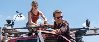 Daisy Edgar-Jones and Glen Powell smiling while working on a truck in the middle of the day in Twisters.