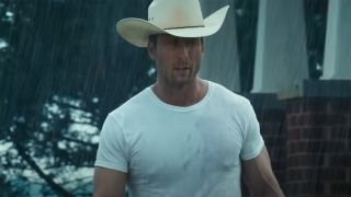 Glen Powell walking through the rain in a white tee in Twisters.